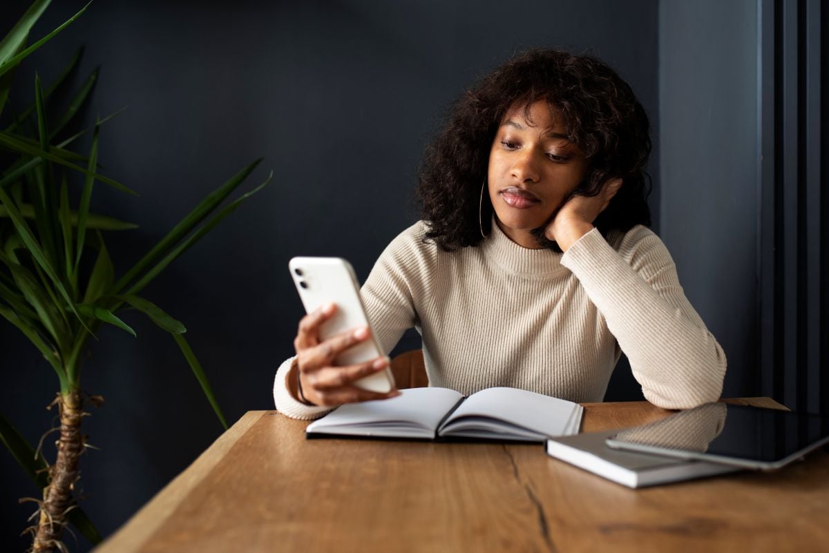 Mulher com livros usando o celular