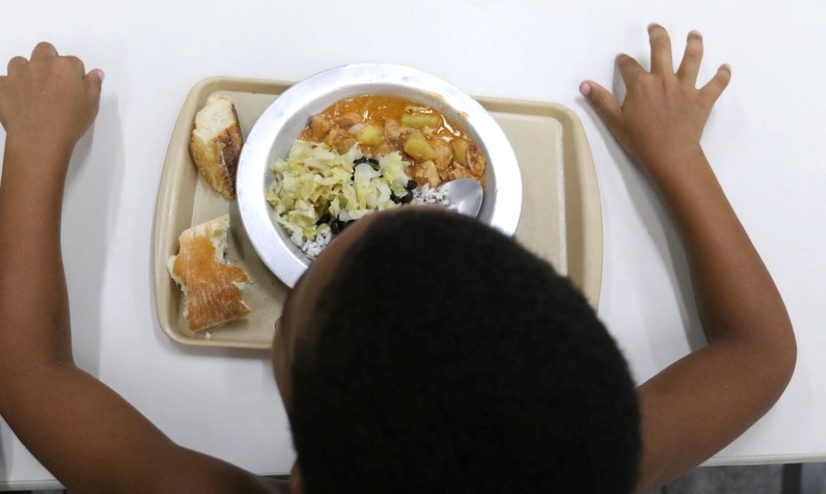 Criança se alimentando com prato de comida na mesa