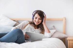 feliz-mulher-jovem-escutar-musica-cama_freepik-300x200-1