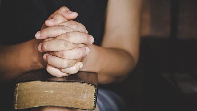 espiritualidade-e-religiao-as-maos-postas-em-oracao-sobre-uma-biblia-sagrada-na-igreja_1150-12794