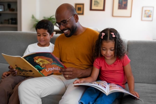 homem-de-tiro-medio-e-criancas-lendo-quadrinhos-em-casa-freepik