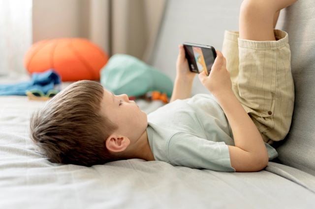 eKE2sQjo-medium-shot-boy-with-smartphone-crianca-com-o-celular-no-quarto-foto-freepik