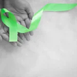 maos-segurando-uma-fita-verde-esmeralda-ou-verde-jade-em-um-fundo-de-tecido-branco-com-espaco-de-copia_54178-2574