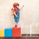 crianca-com-foguete-de-papel-brincando-dentro-de-casa_411285-1853