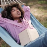mulher-relaxando-na-rede-enquanto-acampa-ao-ar-livre-com-um-livro
