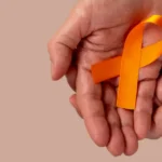 maos-segurando-uma-fita-laranja-para-aumentar-a-conscientizacao-sobre-a-leucemia_146714-359