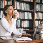 Mulher-bebendo-cafe-em-biblioteca-lendo-livros-Foto-Reproducao-Freepik