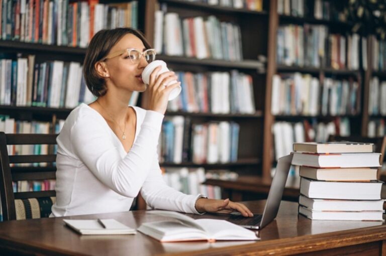 Mulher-bebendo-cafe-em-biblioteca-lendo-livros-Foto-Reproducao-Freepik