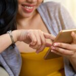 anonymous-filipino-female-browsing-smartphone-acessando-celular-magnifc