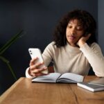 Mulher-com-livros-usando-o-celular-Foto-Reproducao-Magnific-Freepik