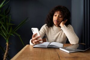 Mulher-com-livros-usando-o-celular-Foto-Reproducao-Magnific-Freepik