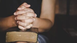espiritualidade-e-religiao-as-maos-postas-em-oracao-sobre-uma-biblia-sagrada-na-igreja_1150-12794
