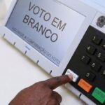 manual-do-eleitor-pessoa-apertando-o-botao-branco-da-urna-eleitoral-etetronica-voto-eleicoes-2026-foto-gerado-com-auxilio-de-IA